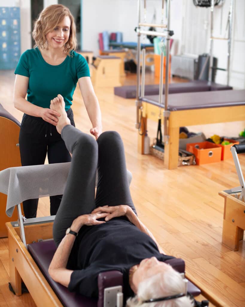 Instructor teaching single leg work on reformer