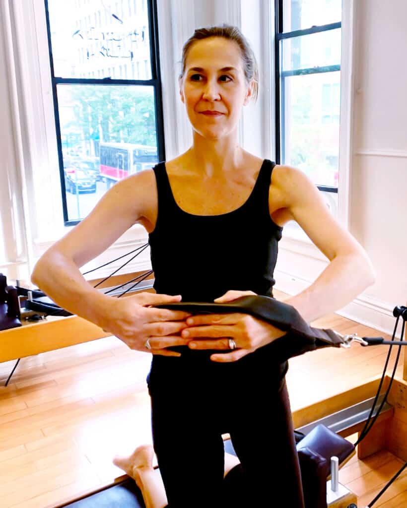 Instructor performing kneeling side rotation on the Reformer. Covid-19 Vaccination Required